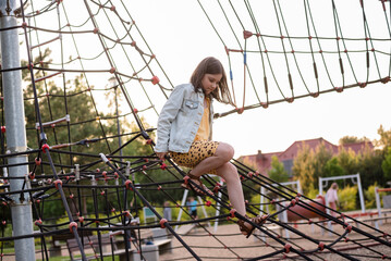 A happy girl at a playground. The girl is playing on net ropes.