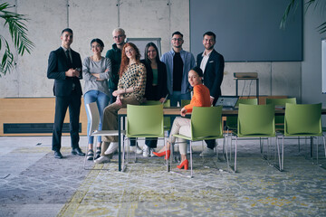 A diverse group of successful businesspeople gather and pose for a photo, showcasing teamwork and professional empowerment in a modern office setting.