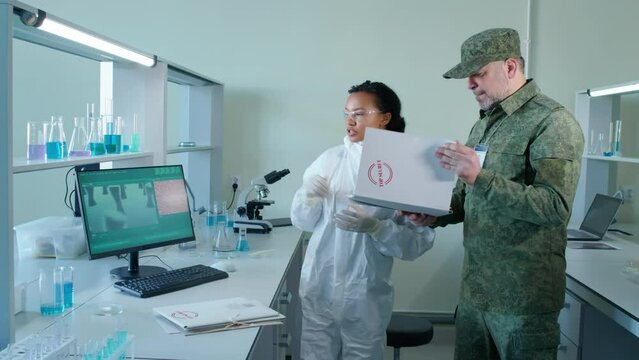 Full shot of Biracial female scientist in protective suit telling military Caucasian man about results of secret project
