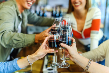 Crop and unrecognizable friends clinking wineglasses in restaurant