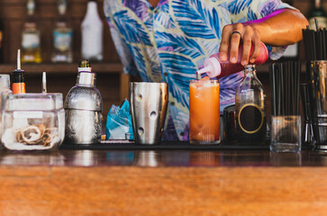 Bartender making cocktail topping with grenadine syrup at the bar.