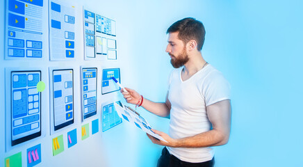 Man designer. Mobile application developer. Guy is looking at sketches of website. Web application...