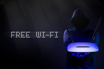 Free Wi-Fi. Hacker is holding a router in his hands.  Vulnerabilities in wireless internet. - obrazy, fototapety, plakaty