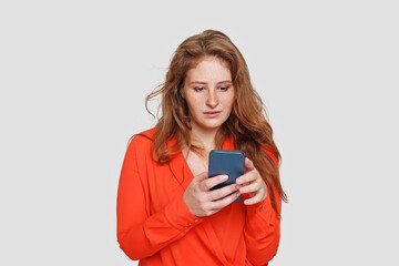 Fototapeta premium Attractive woman using app on her smartphone on white background