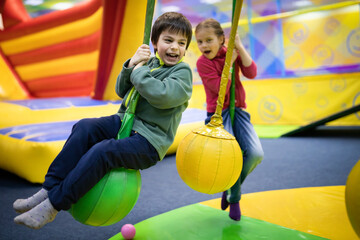 Fototapeta na wymiar Little smiling boy and girl having fun in amusement center for kids