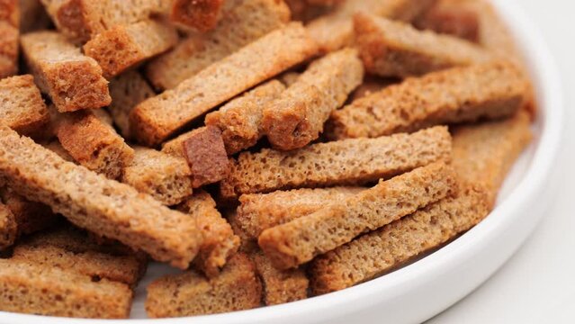 Crispy toasted bread croutons. A pile of hard rusks from dark dry bread close up. Snack for beer. Rye crackers. Snacks rye crackers in a strip. Crouton or brown roasted tostes rotating. 