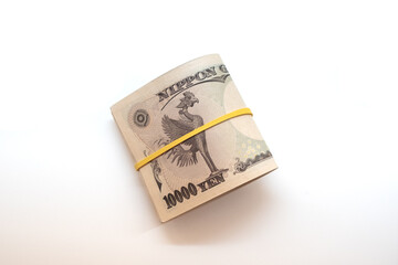 Wad of Japanese yen bills on a white table with space for text. Money concept.