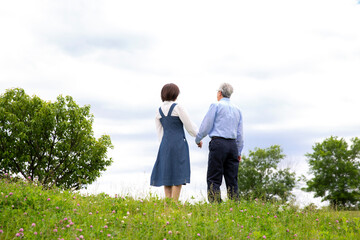 日本人ミドル夫婦の後ろ姿、公園で手を繋ぎ全身、