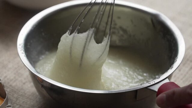 mixing sugar with egg white with hand mixer pastry in metal container, slow motion, close up, natural light