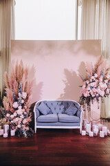 Wedding. Decor. In the lounge area there is a sofa and a arrangement of pink and blue flowers with branches of greenery