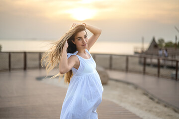 Portrait of a beautiful young pregnant woman in a white dress enjoying the breeze on the beach...
