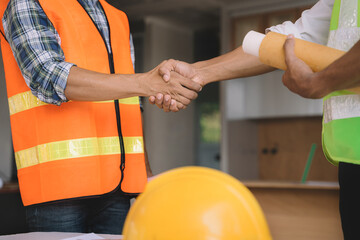 construction worker wearing a protective helmet and vest is holding his colleague's hand while working at the job site.