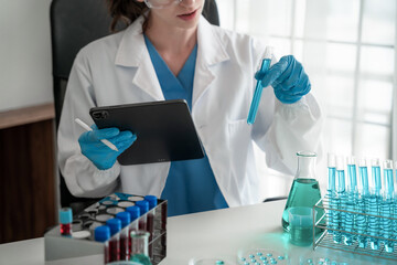 Fototapeta premium Chemist scientist holding test tube and tablet conducting experiment in laboratory with equipment, science concept.