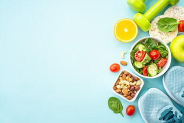 Healthy lifestyle and diet food background. Sport shoes, dumbell and healthy food on blue. Flat lay...