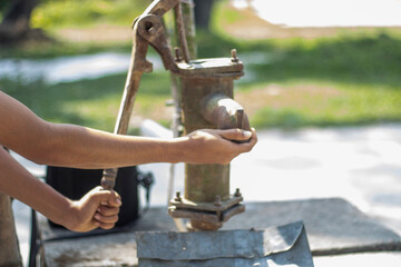 A man is trying to squeeze water out of a tube well with his two hands