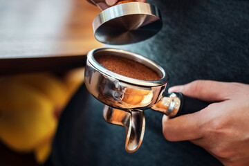 Close-up of hand Barista cafe making coffee with manual presses ground coffee using tamper at the coffee shop