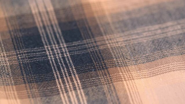 flannel fabric with a checkered pattern of beige brown color. rotating texture of cotton checkered material. close-up. fabric background of textile production.