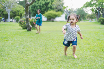 Happy girl running on green grass in the park Cheerful children in the meadow in the park under the sunlight. Child playing on spring grass, young woman's sprint at sunset in evening backyard.