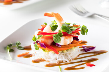 A deconstructed salad roll stack with Asian dressing drizzled on a plate.