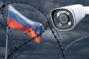 Barbed wire with a security camera on the background of the flag of Russia.