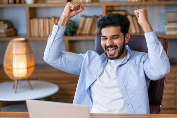 Excited indian business man looking at laptop celebrating win accomplishment victory with yes...