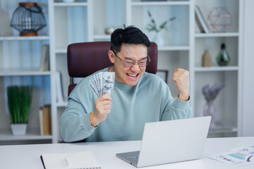 Satisfied asian employee receives bunch of money on payday. Handsome happy businessman counts money banknotes working at modern office corporation