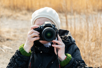 Aged woman with a camera. Outdoors. Selective focus.