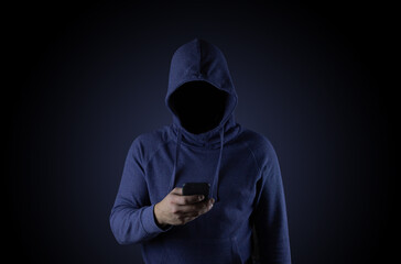 A hacker in a blue hood is holding a phone. Phone fraudster.