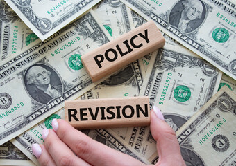 Policy revision symbol. Concept word Policy revision on wooden blocks. Beautiful dollar background. Businessman hand. Business and Policy revision concept. Copy space