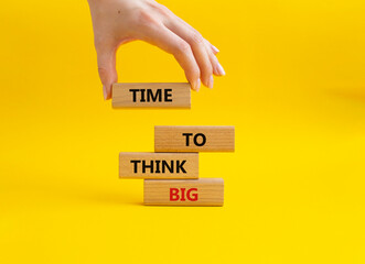 Time to think big symbol. Wooden blocks with words Time to think big. Beautiful yellow background....