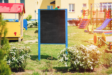 Empty black chalkboard with mockup space stands outdoor of school building for children creativity.