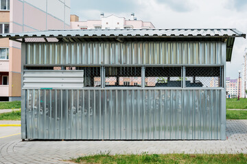 Trash containers block for flat garbage collect behind metal fence on courtyard of residential house or condominium