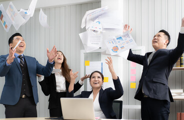 Business people happy celebrate their achievement by throwing success project paper document in the air. Asian businessman and teamwork together excited celebrating successful sales growth. copy space