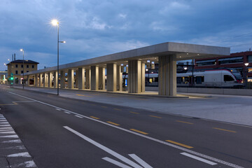 Modern bus stop shelter with the train station behind it in Mendrisio. Modern infrastructure in Switzerland.