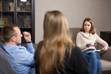 Woman specialist analyzes and explains problems in relationship. Couple of man and woman sitting on...