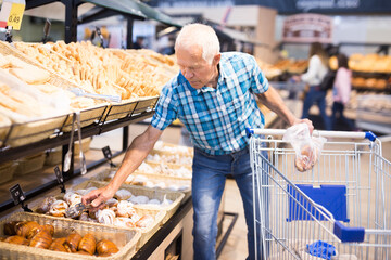 elderly man buying bread and pastries in grocery section of the supermarket