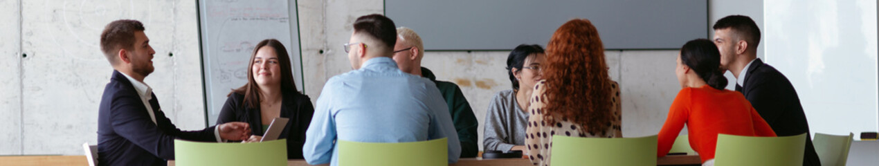 Wide crop photo of a diverse group of business professionals gathered at a modern office for a...