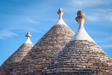 Fototapeta na wymiar Conical roofs of trulli houses with traditional pinnacles, Alberobello, Bari, Italy.