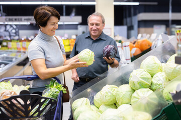 husband and wife choose cabbage in vegetable department