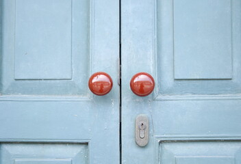 Red brown round shape door knob on painted light blue wood door closed.