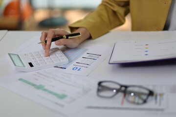Businesswoman doing accounting work in the office analyzing charts in financial reports with a...