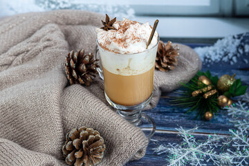 Hot coffee latte with cinnamon sticks, sprinkled with cinnamon. Christmas decorations, branches of...