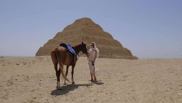 Woman is standing and smiling with a horse. Djoser Step pyramid.