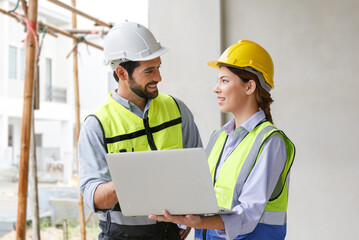 Team of industrial engineers men and women wearing helmets discussing new projects. while using laptop