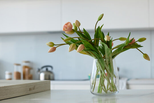 Close-up of beautiful flowers in glass vase standing on table in domestic kitchen