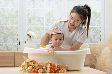 Adorable of asian newborn baby bathing in bathtub.mother bathing her son in warm water.Happy...