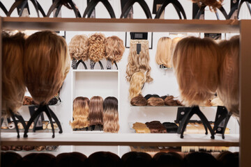 Showcase of natural looking wigs in different colors fixed on the metal wig holders in beauty...