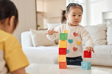 Asian little girl playing with colorful blocks in the living room at home