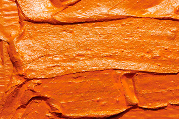 Decorative orange putty background. Wall texture with filler paste applied with spatula, chaotic...