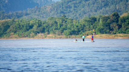 3 Asians on a pirogue on the mekong river in Luang Prabang, Laos